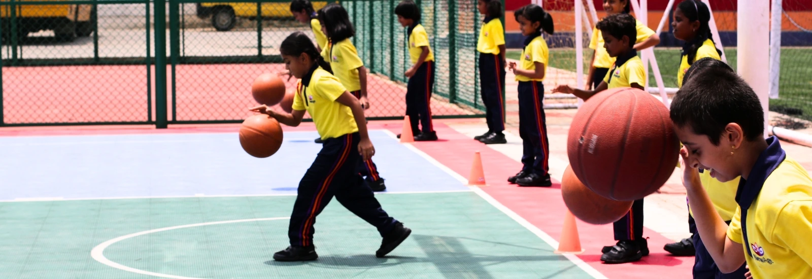 Students at NewAge World School engaged in a basketball dribbling drill on the outdoor court, enhancing their coordination and sports skills.